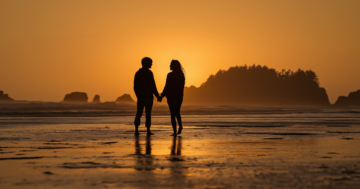 Silhouette of a couple holding hands at sunset on the beach